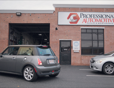 Professional Automotive shop with a gray Mini Cooper parked in front of the bay and a silver car parked on the right.