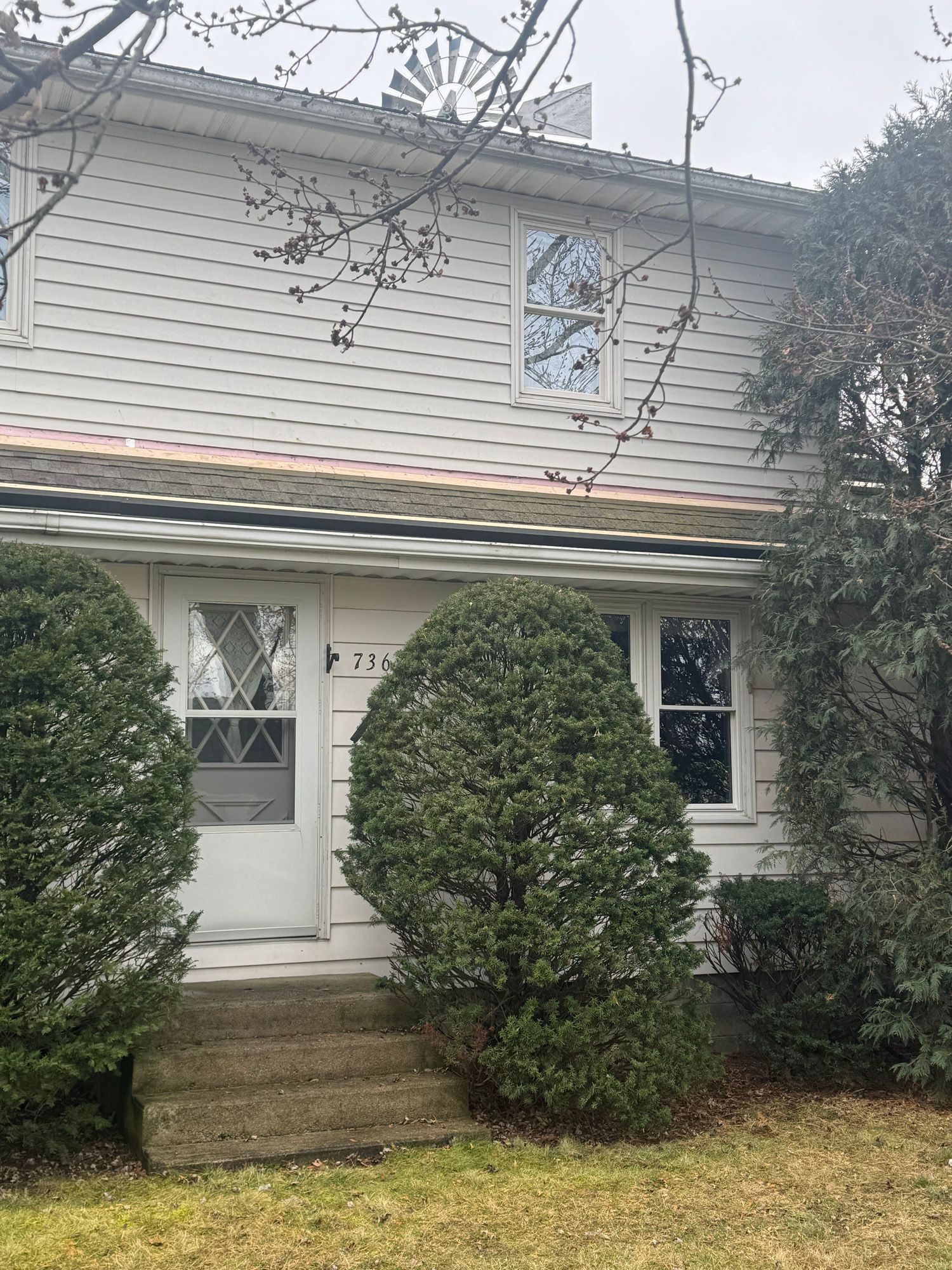 A white house with a lot of bushes in front of it.