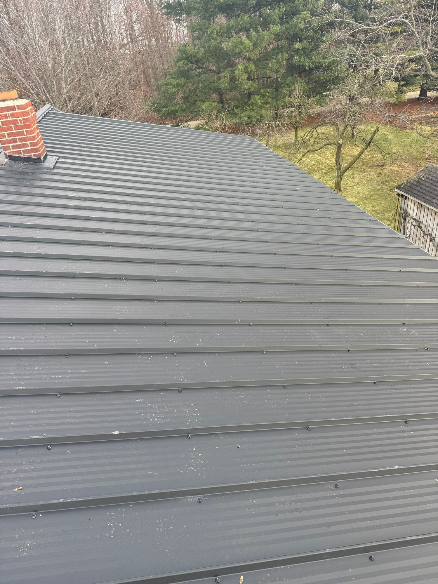 A black metal roof with a chimney on top of it.