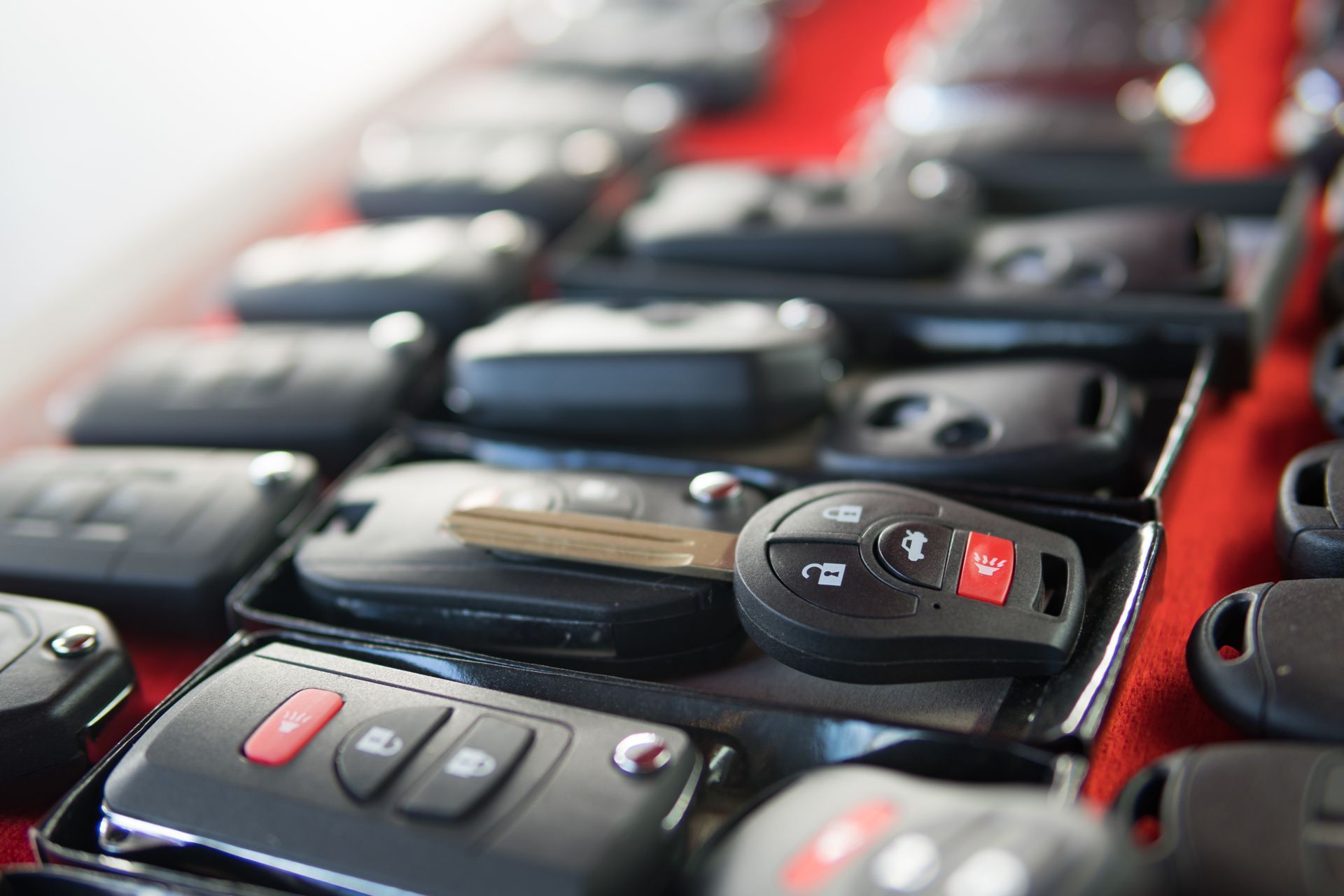 Close-up of a display of car key fobs, mostly black with red buttons