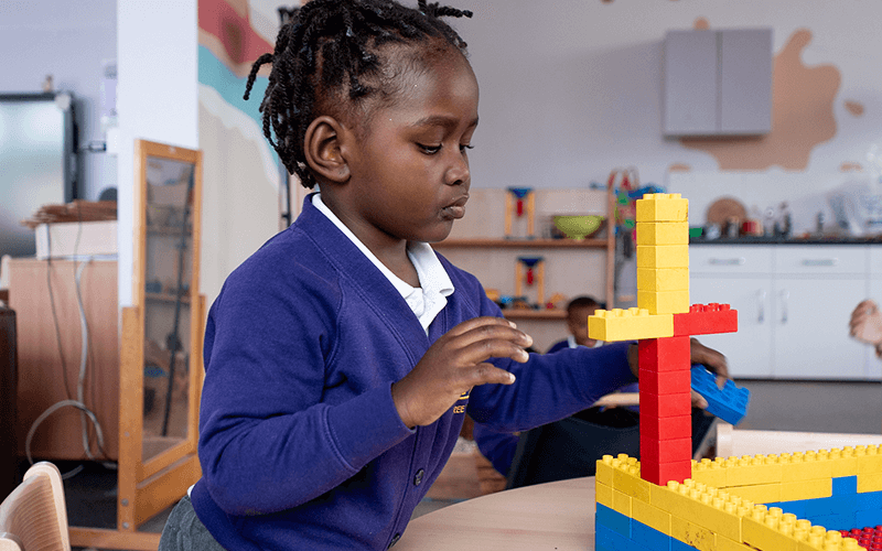 A young girl is playing with lego blocks at a table.