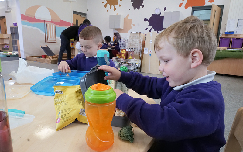 Two young boys are playing with toys at a table in a classroom.