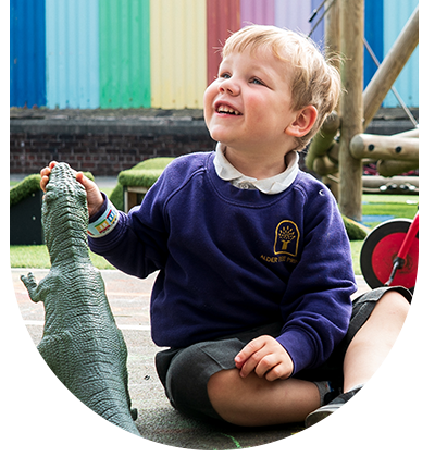 A young boy is sitting on the ground holding a toy dinosaur.