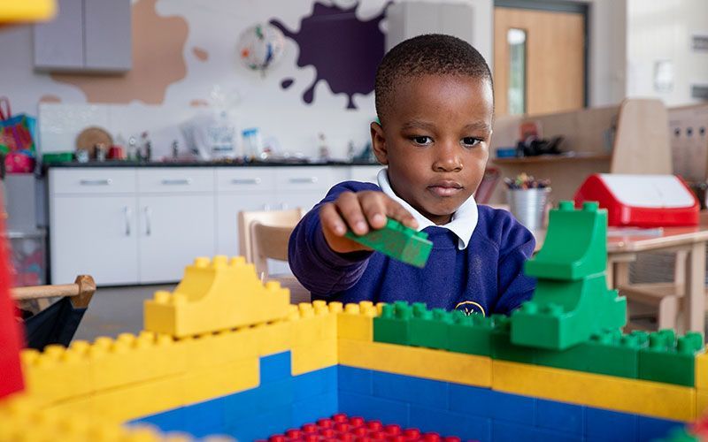 A young boy is playing with lego blocks in a classroom.