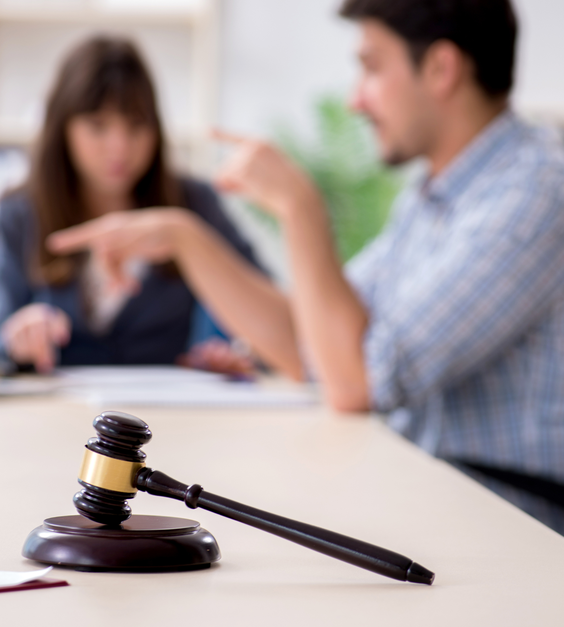 A man and a woman are sitting at a table with a judge 's gavel in the foreground.