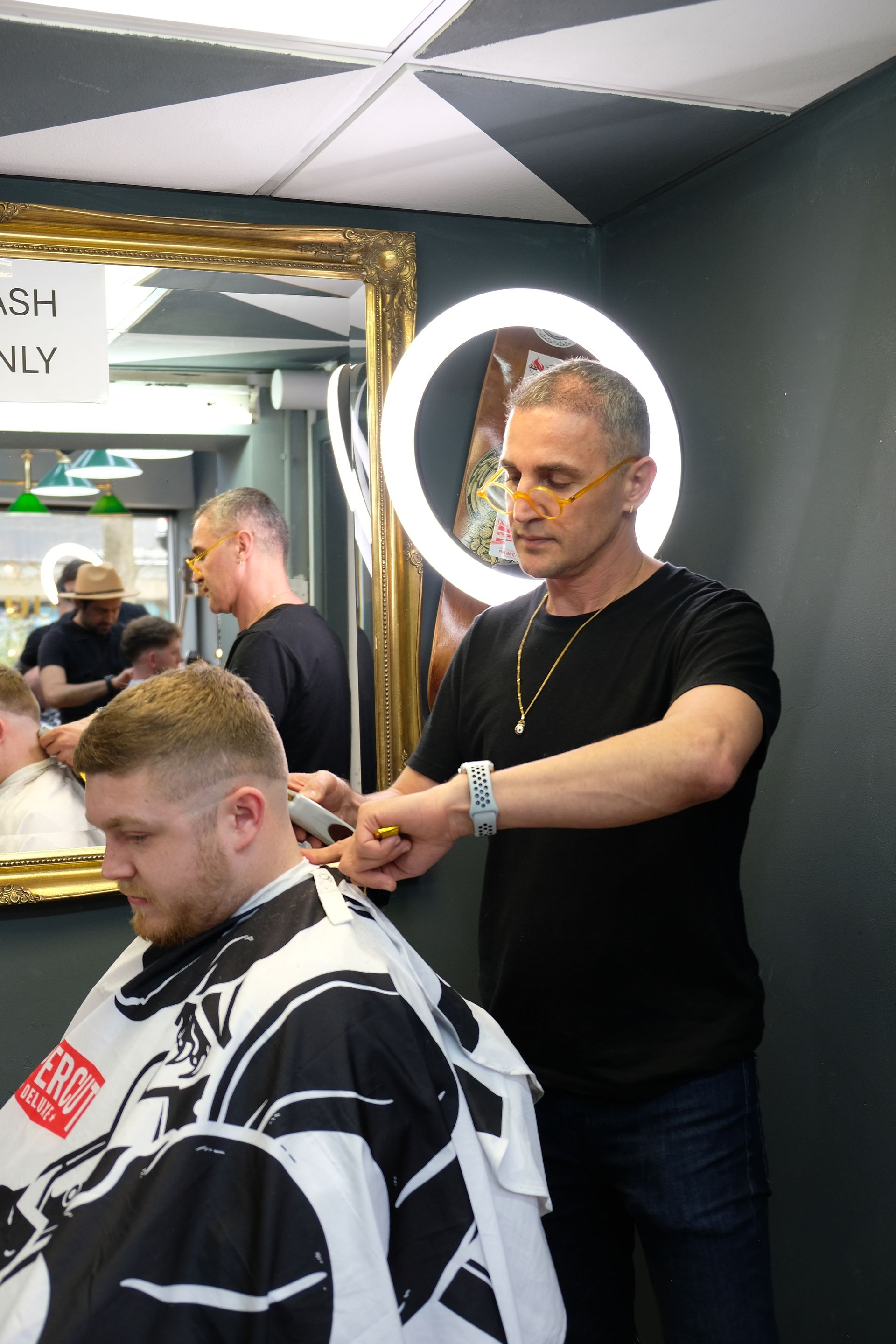A man is getting his hair cut by a barber in a barber shop.