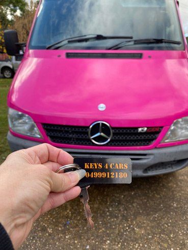 Hand Holding Key with Background of Pink Van — Replacement Car Keys in Wagga Wagga, NSW