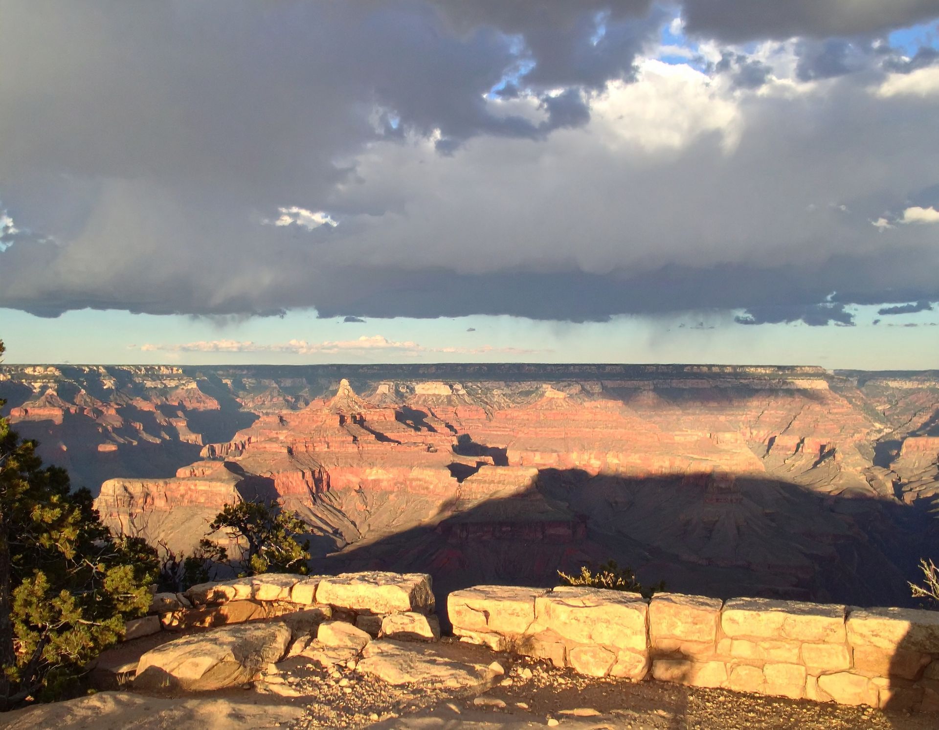 Grand Canyon overlook at sunset with dramatic clouds and sandstone cliffs