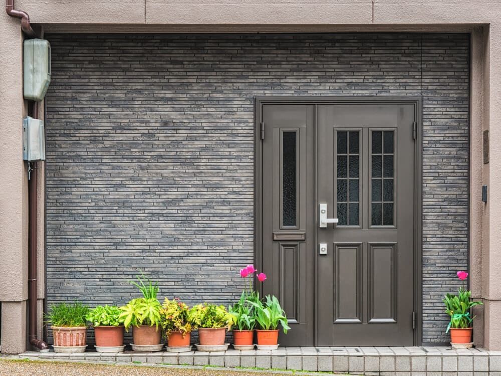 The Front Door Of A House With Potted Plants In Front Of It — Browny's Glass & Aluminium in Hallidays Point, NSW