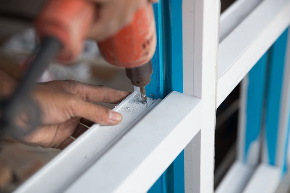 A Person Is Using A Drill To Install A Window Frame — Browny's Glass & Aluminium in Hallidays Point, NSW