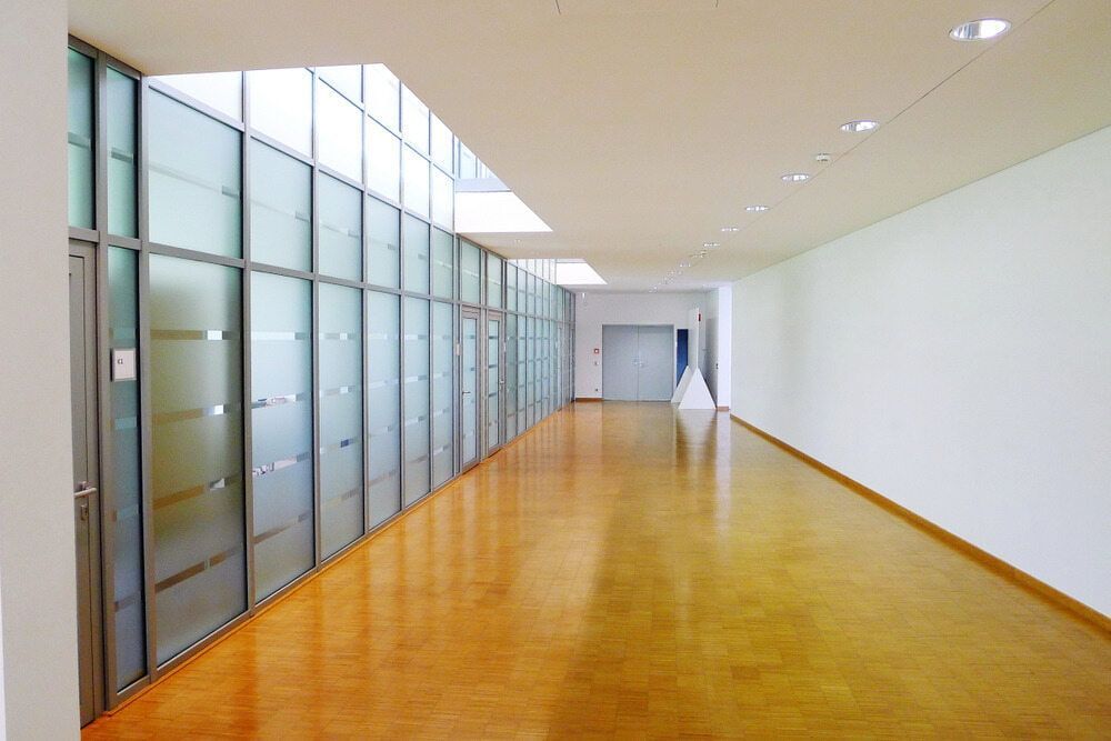 An Empty Hallway With A Wooden Floor And White Walls — Browny's Glass & Aluminium in Gloucester, NSW