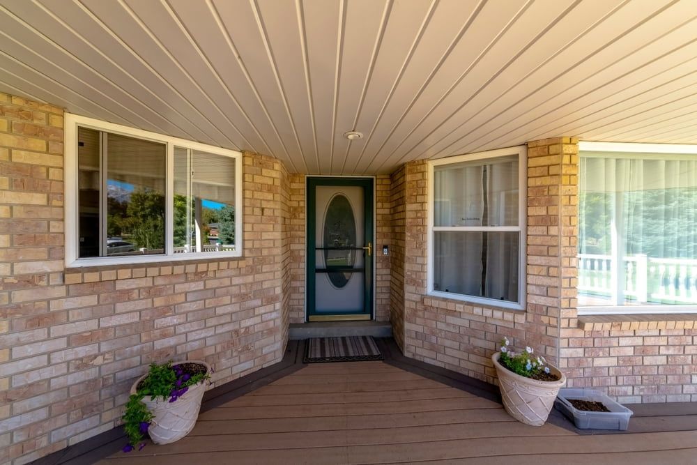 A Brick House With A Porch And A Green Door — Browny's Glass & Aluminium in Hallidays Point, NSW