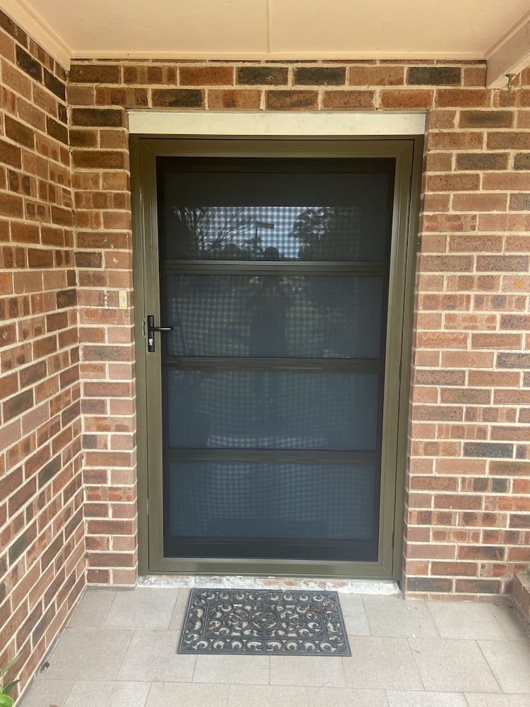 A brick wall with a screen door on it — Browny's Glass & Aluminium in Taree, NSW