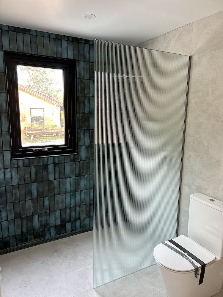 A Bathroom With A Toilet, Shower And Window — Browny's Glass & Aluminium in Wingham, NSW