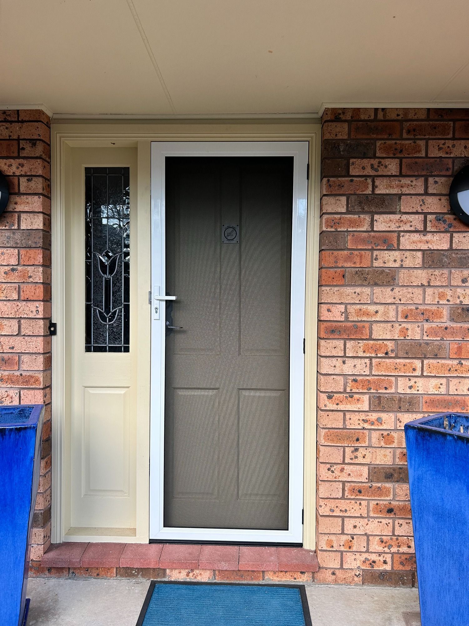 A Blue Screen Door Is On The Side Of A House — Browny's Glass & Aluminium in Old Bar, NSW