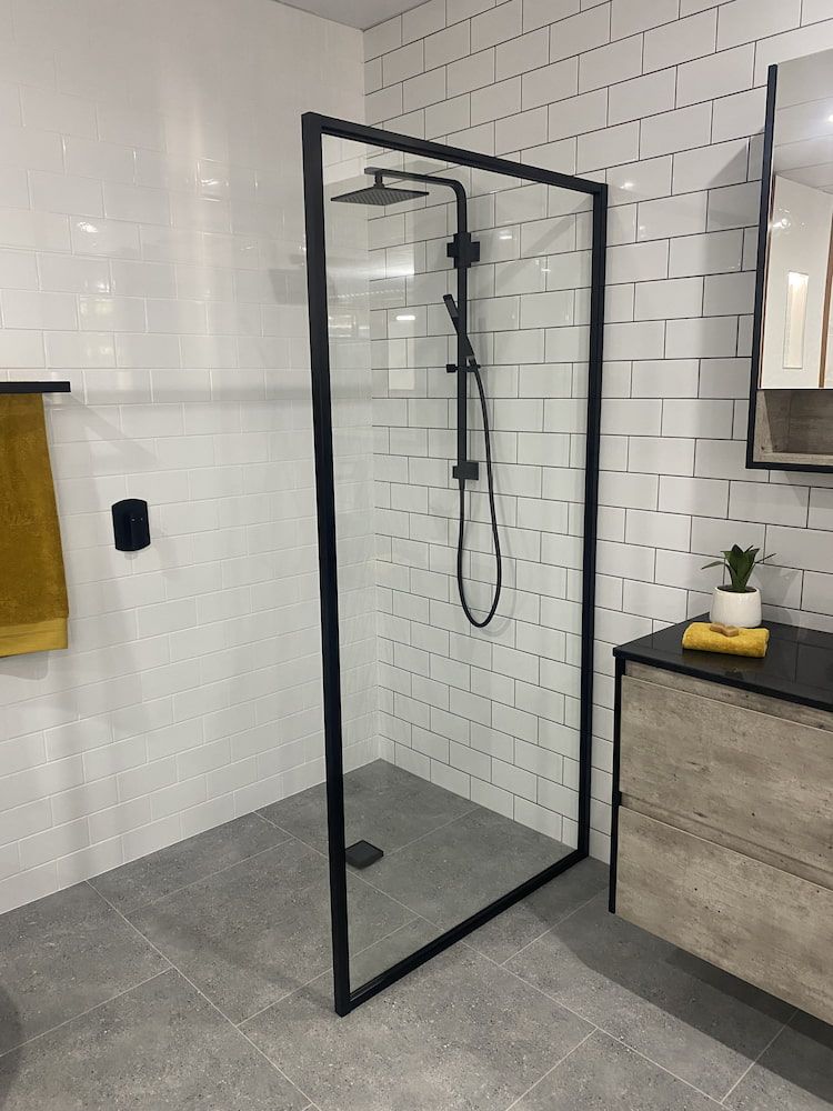 A Bathroom With White Tiles And A Walk In Shower With A Black Frame — Browny's Glass & Aluminium in Wingham, NSW