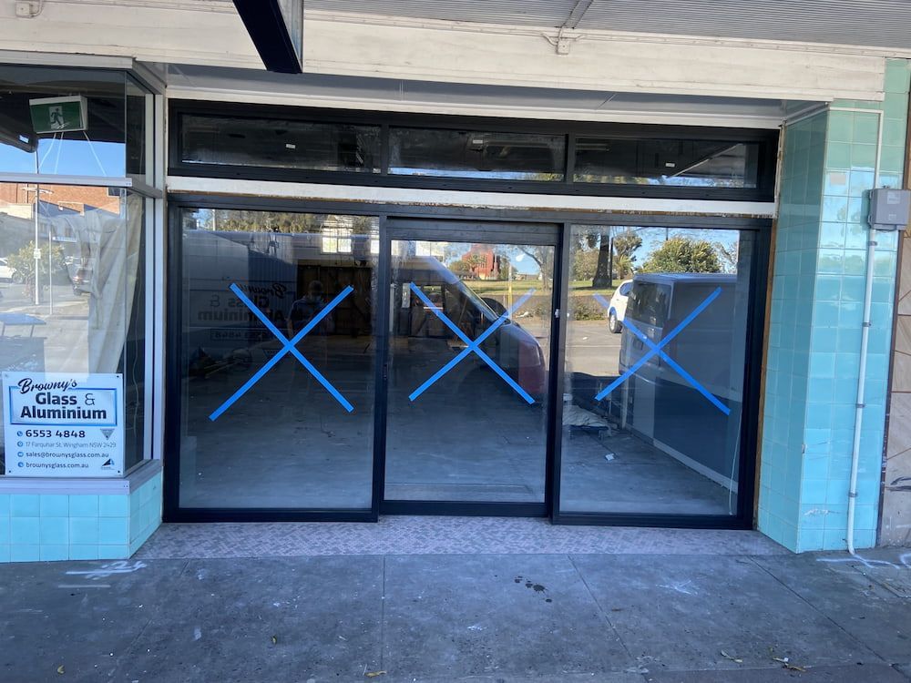 A Building With A Sliding Glass Door And A Sign That Says Glass Design — Browny's Glass & Aluminium in Wingham, NSW