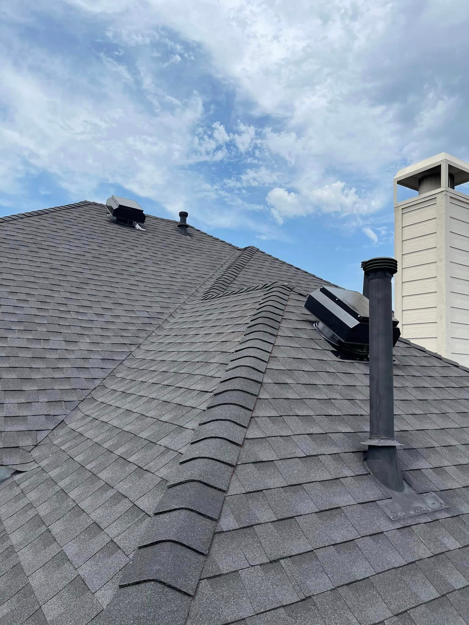 A roof with a chimney on top of it and a blue sky in the background.