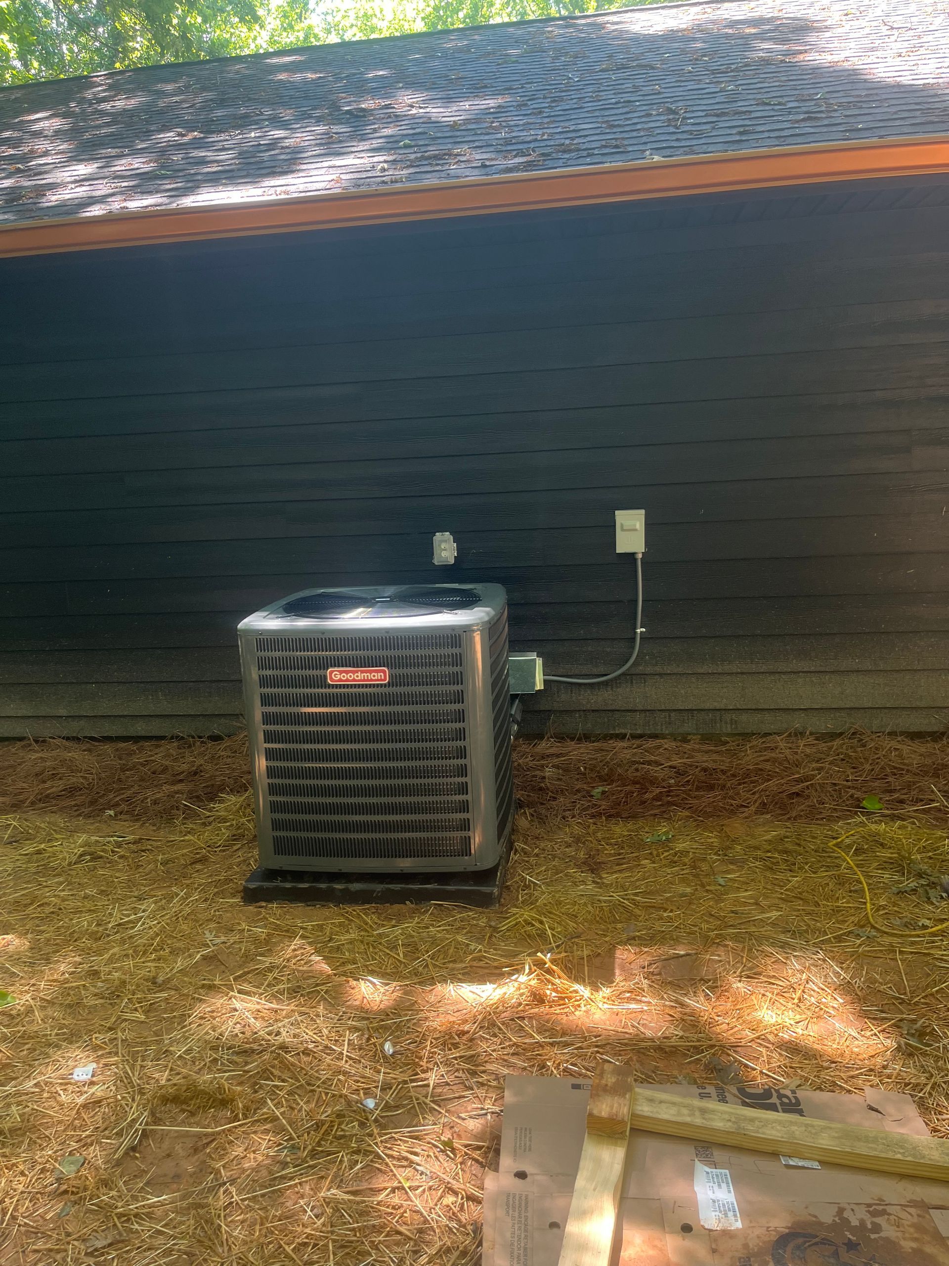 Bryant air conditioning unit sits next to a dark gray house.