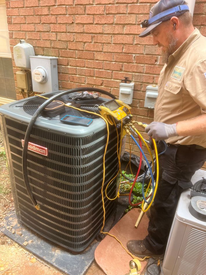 A person wearing blue gloves is fixing an air conditioner with a screwdriver.