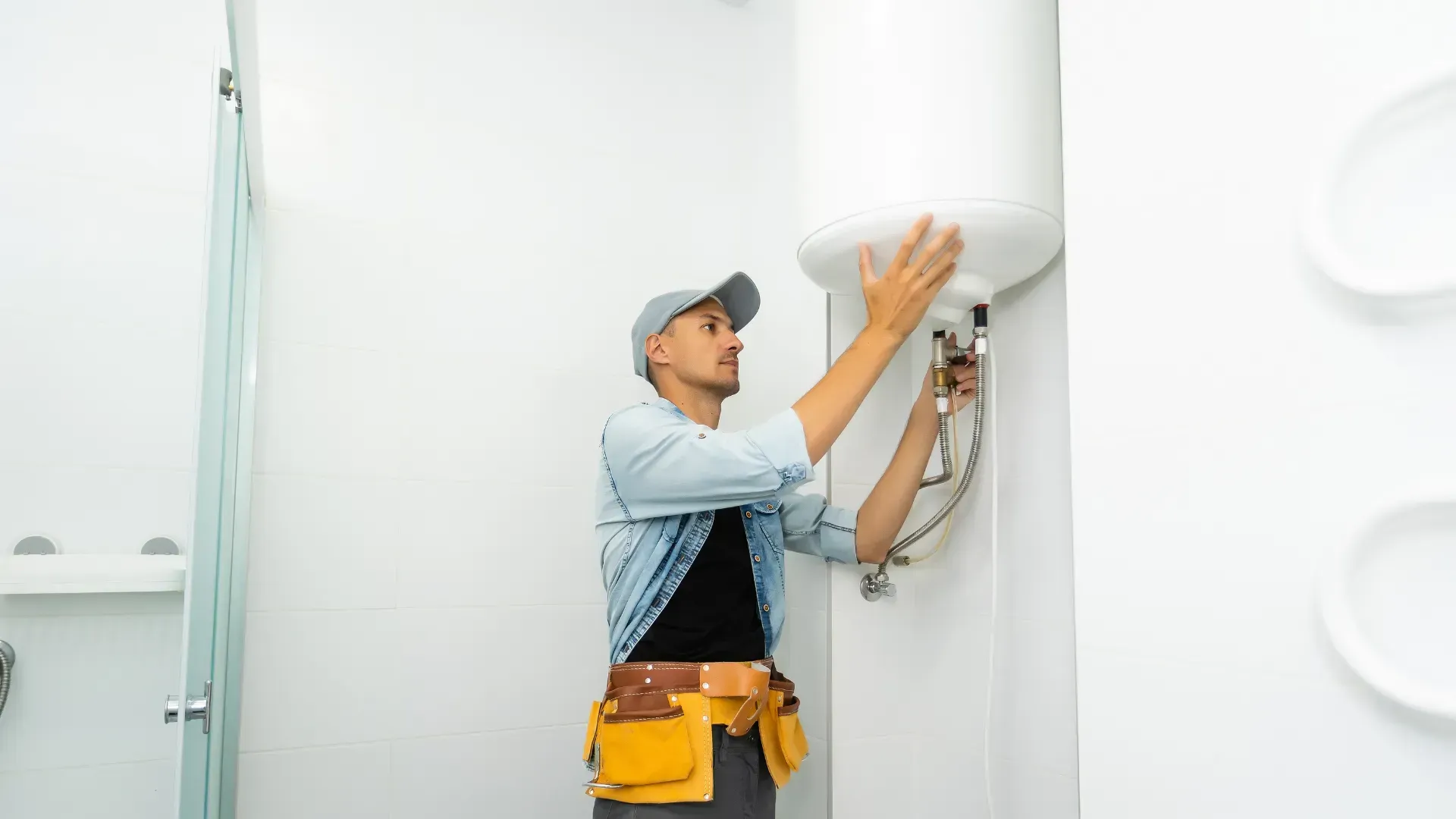 A man is installing a water heater in a bathroom.