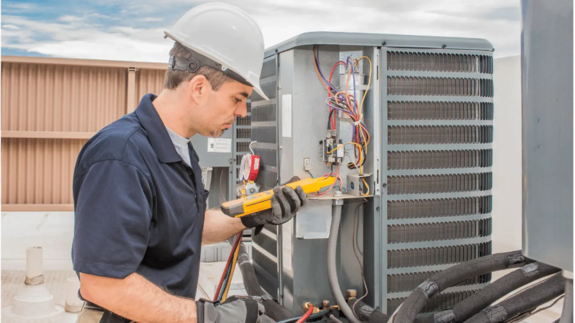 A man in a hard hat is working on an air conditioner.