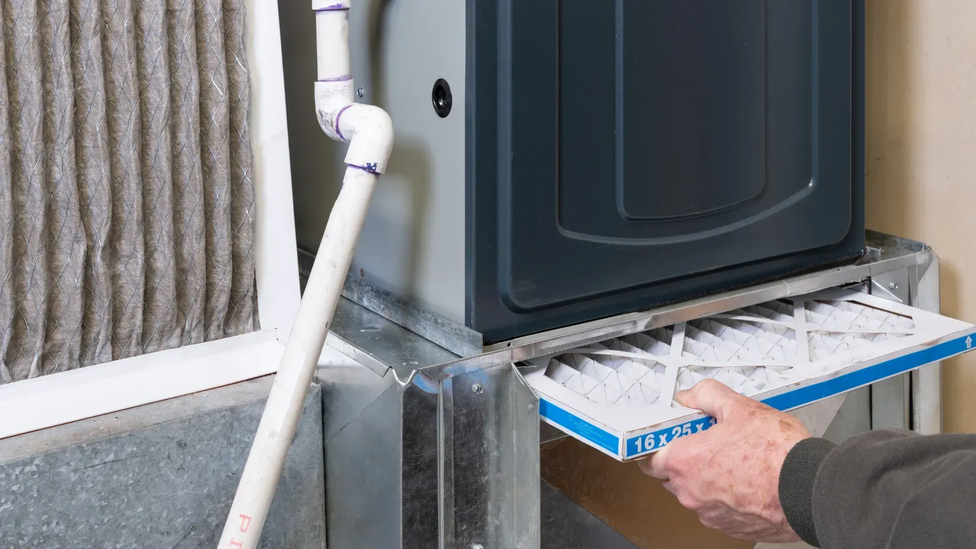 A person is changing a filter on a furnace.