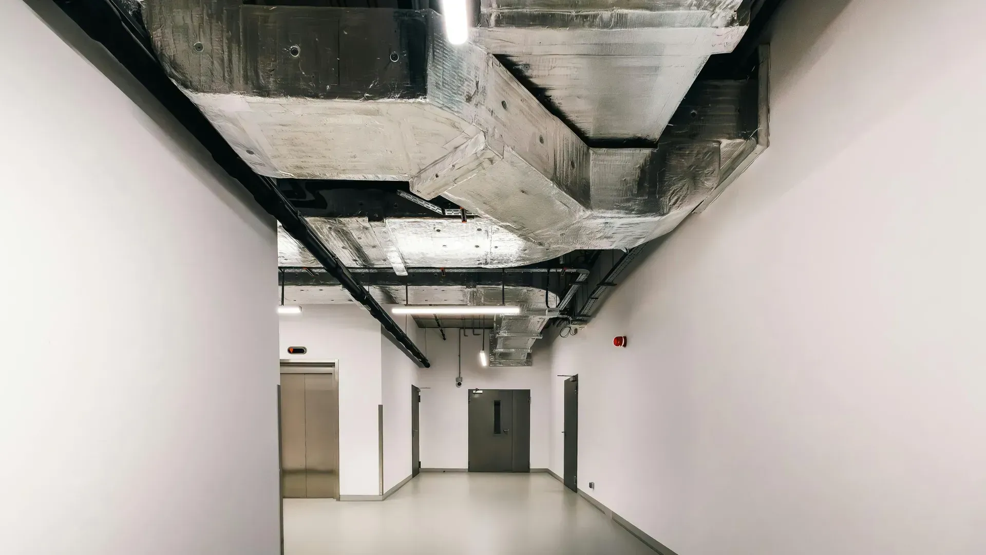 An empty hallway with a ceiling fan and a door.
