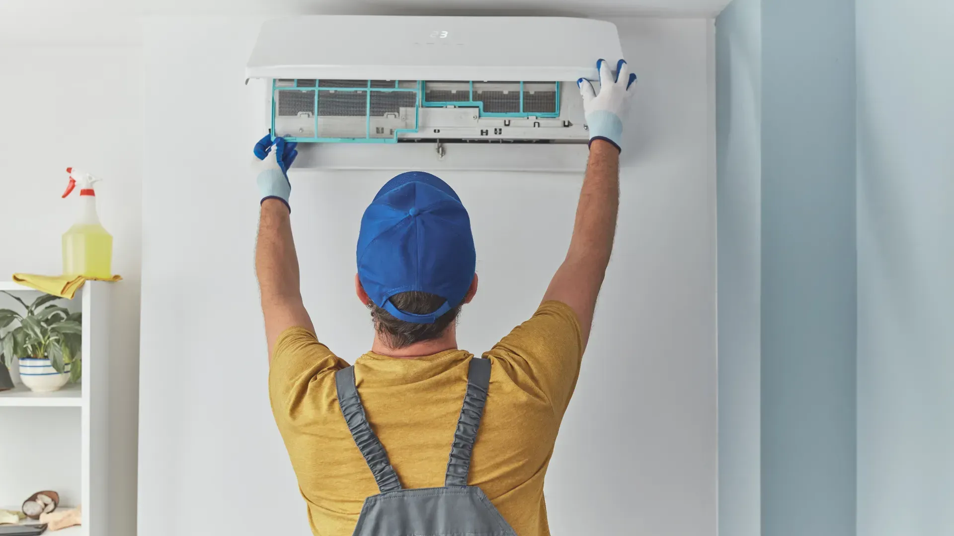 A man is cleaning an air conditioner in a room.