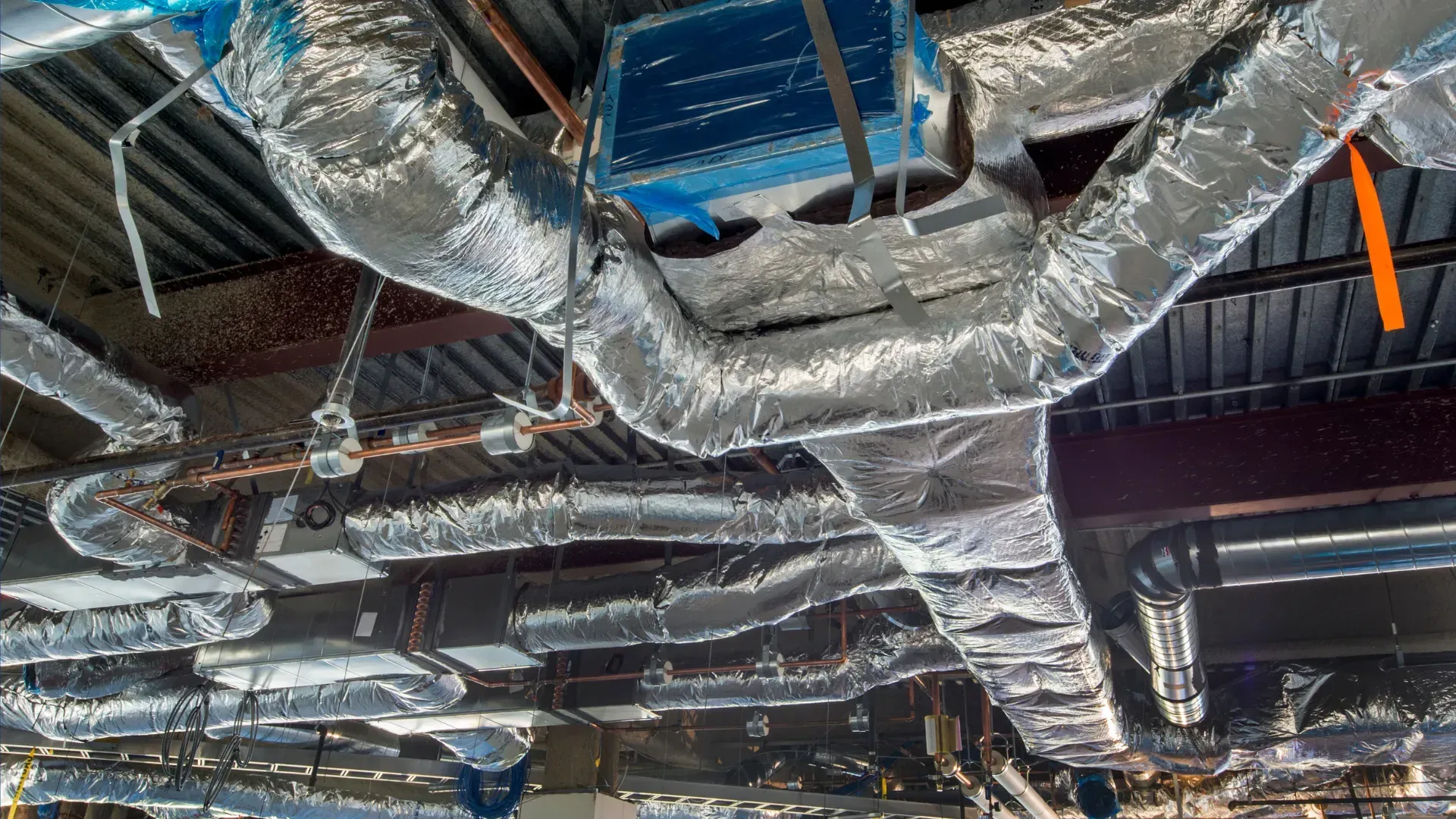 A bunch of pipes are hanging from the ceiling of a building.