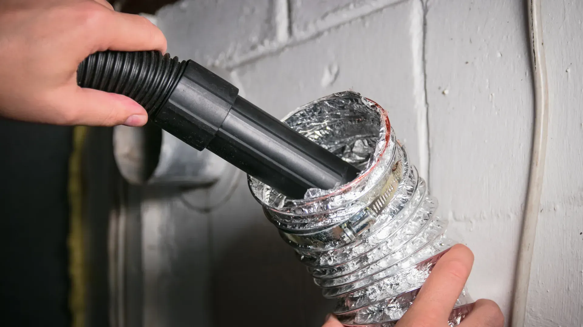 A person is using a vacuum cleaner to clean a duct.