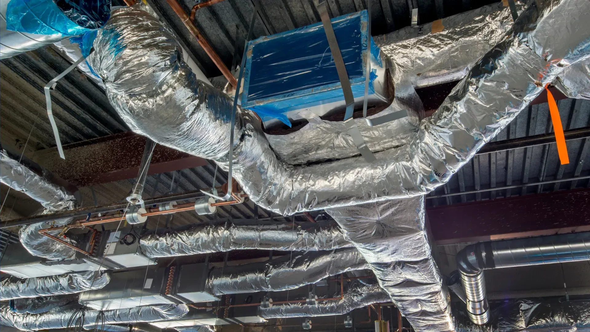A bunch of ducts are hanging from the ceiling of a building.