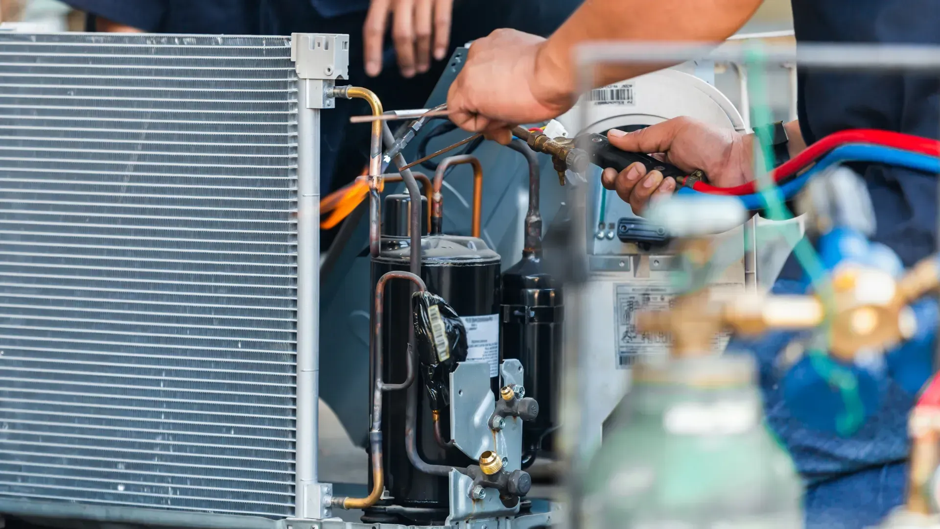 A man is working on an air conditioner with a wrench.