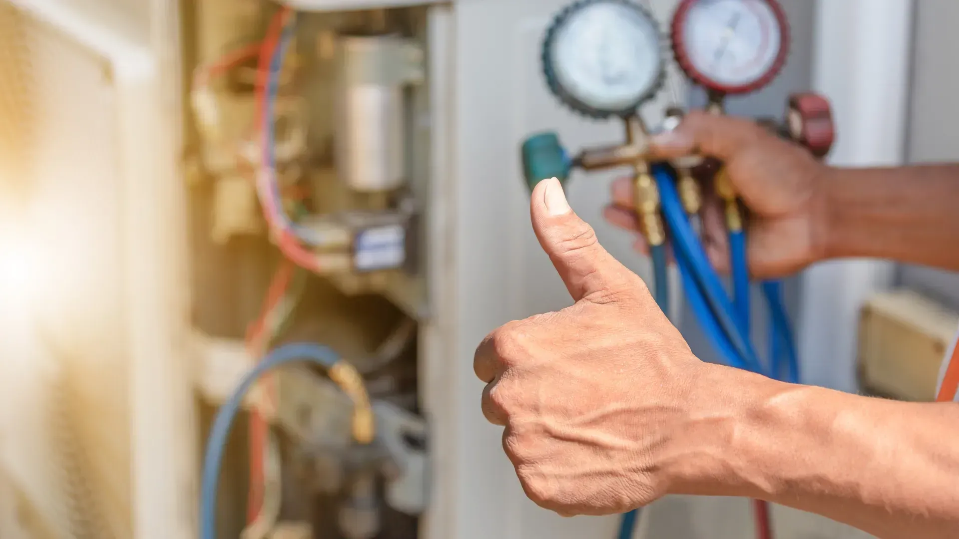 A man is giving a thumbs up while working on an air conditioner.