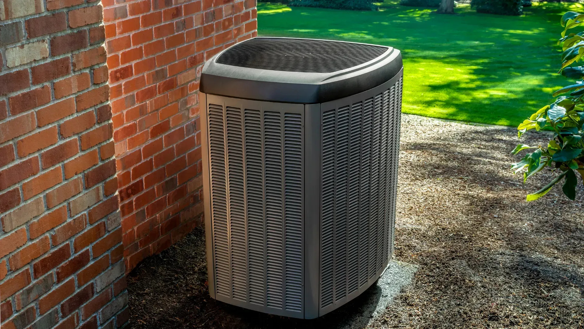 An air conditioner is sitting on the side of a brick building.