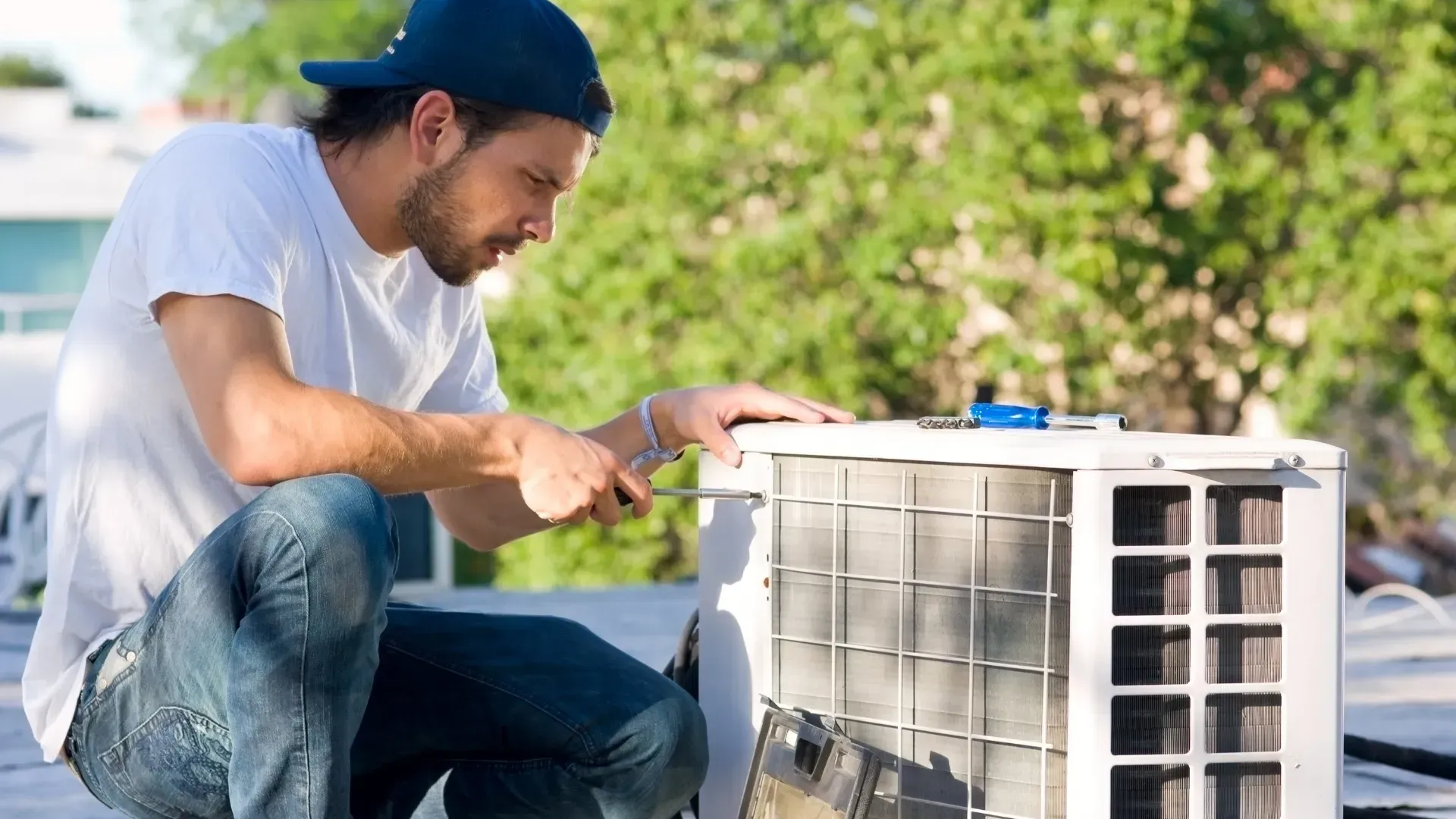 A man is working on an air conditioner on a roof.