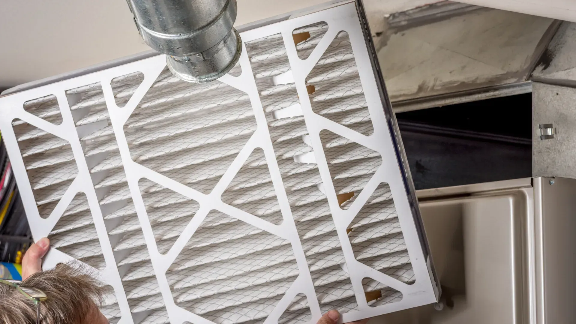 A person is cleaning an air filter in a room.