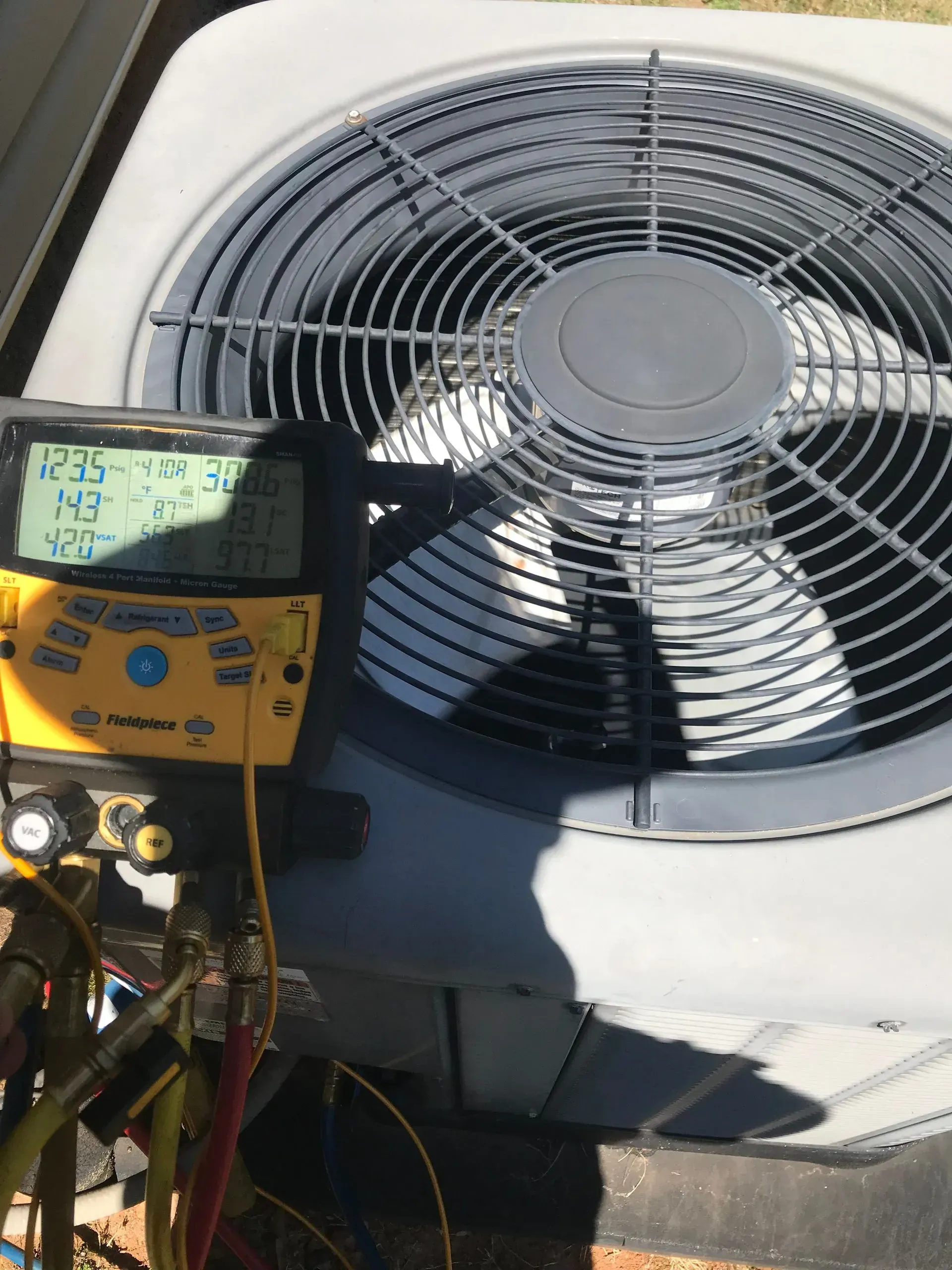 A thermometer is sitting on top of an air conditioner.