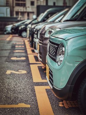 A row of cars parked in a numbered lot, with a light green vehicle in the foreground.