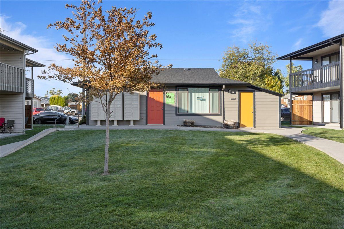 Courtyard lawn between apartment buildings with a small tree and a colorful entrance building in the center