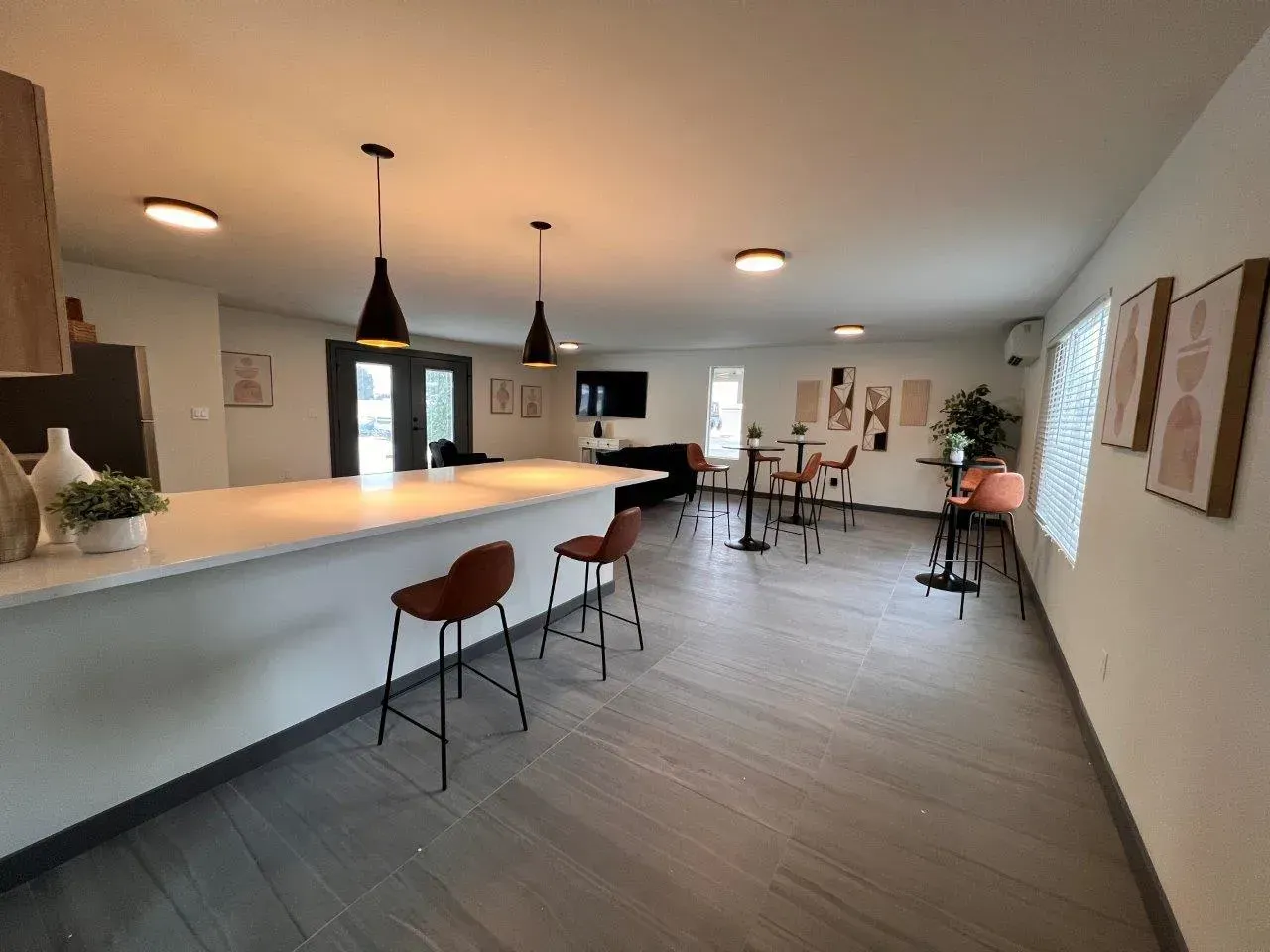 Modern open-plan kitchen and dining area with a large island, pendant lights, and gray wood flooring.