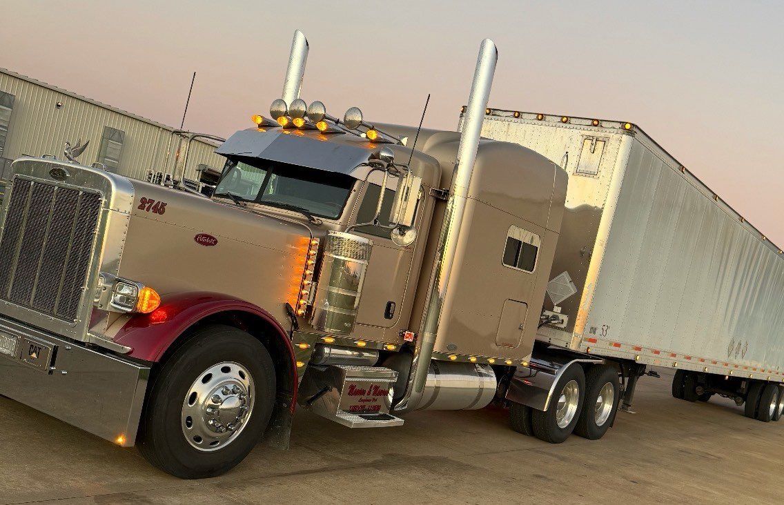 A dark blue semi-truck parked next to a loading dock.