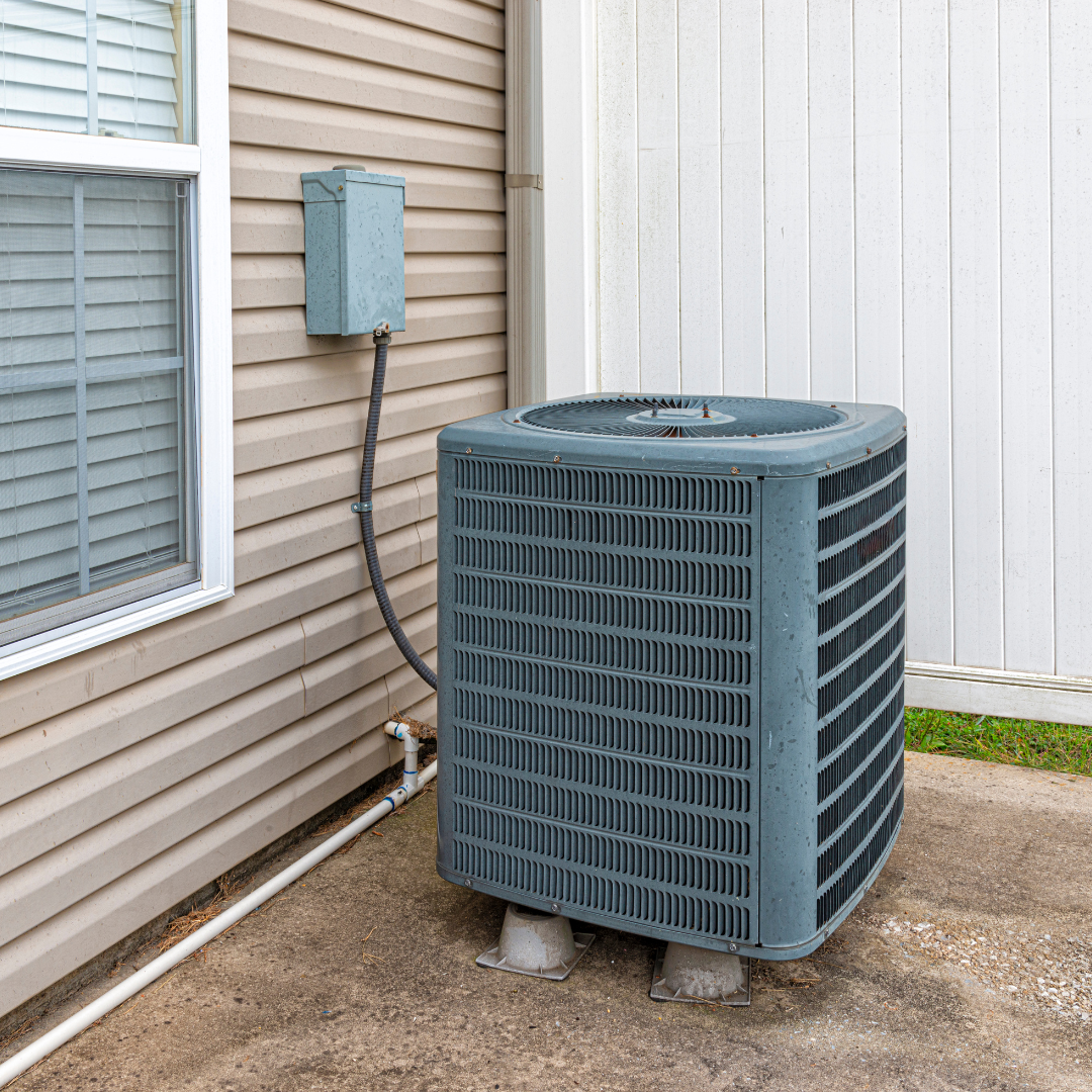 An air conditioner is sitting outside of a house next to a window.