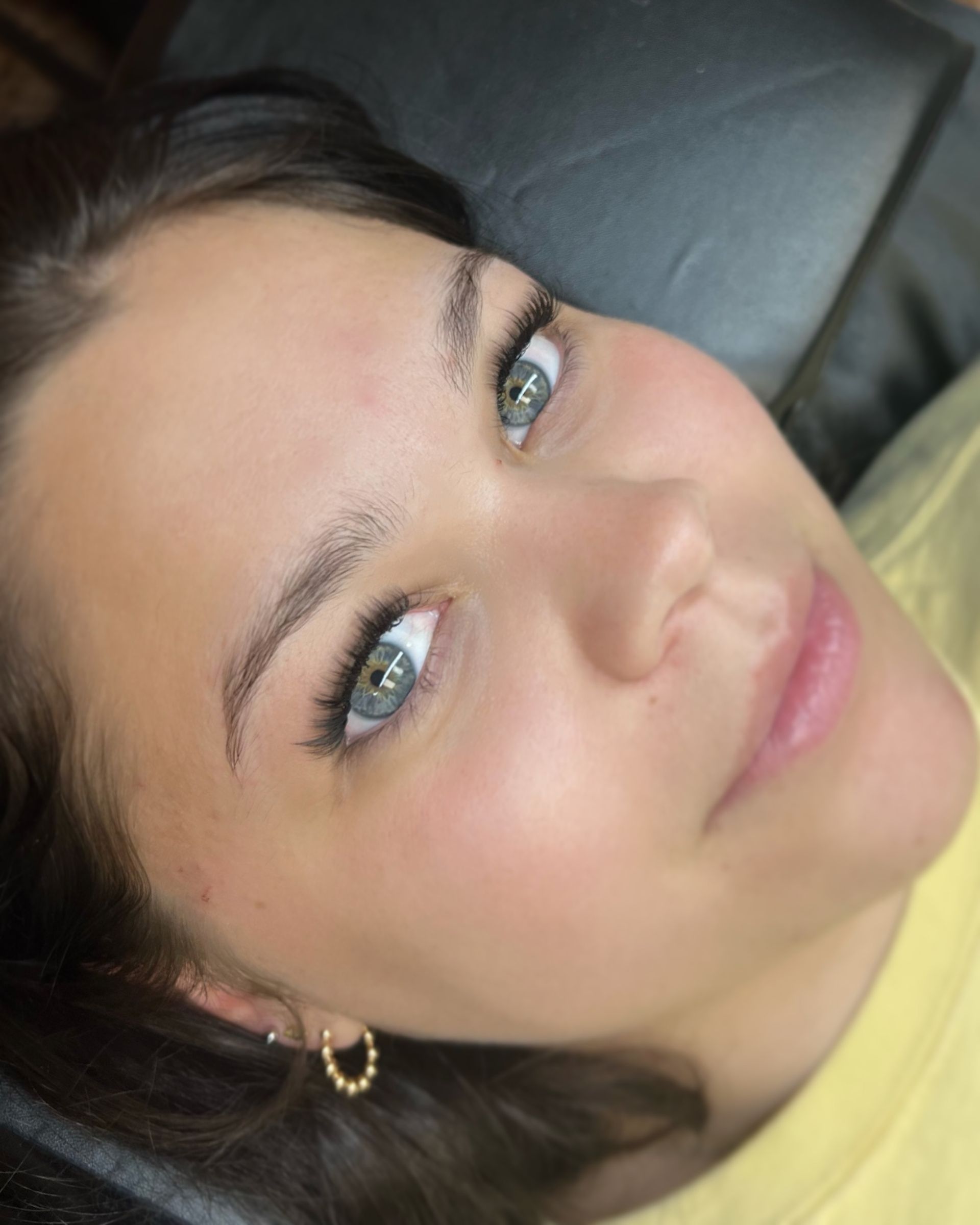 A close up of a woman 's face with blue eyes and earrings.