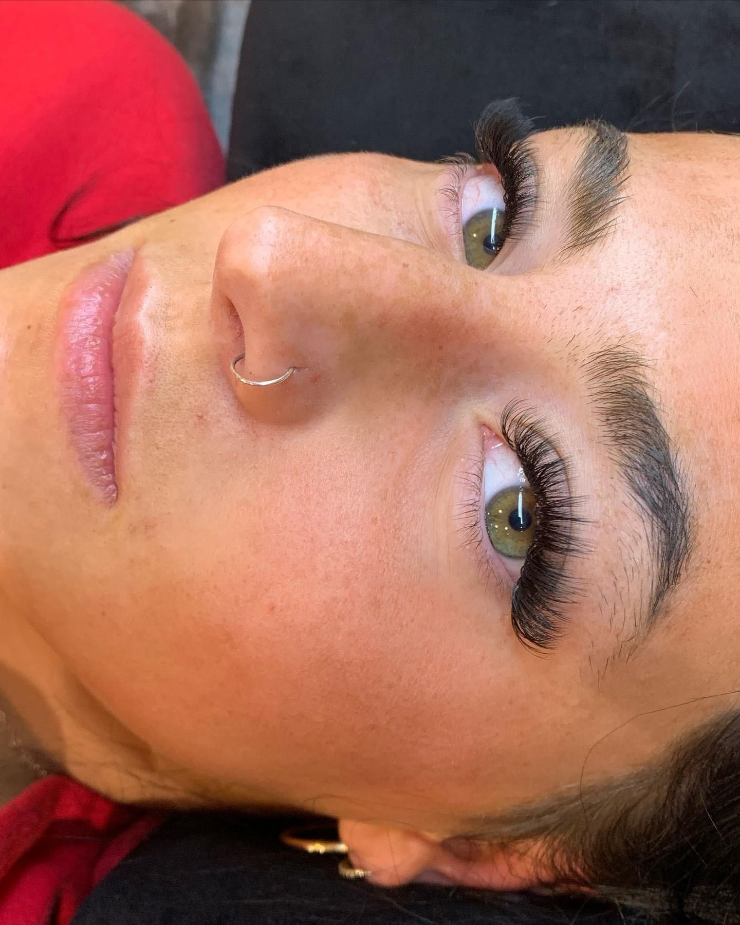 A close up of a woman 's face with long eyelashes and a nose ring.