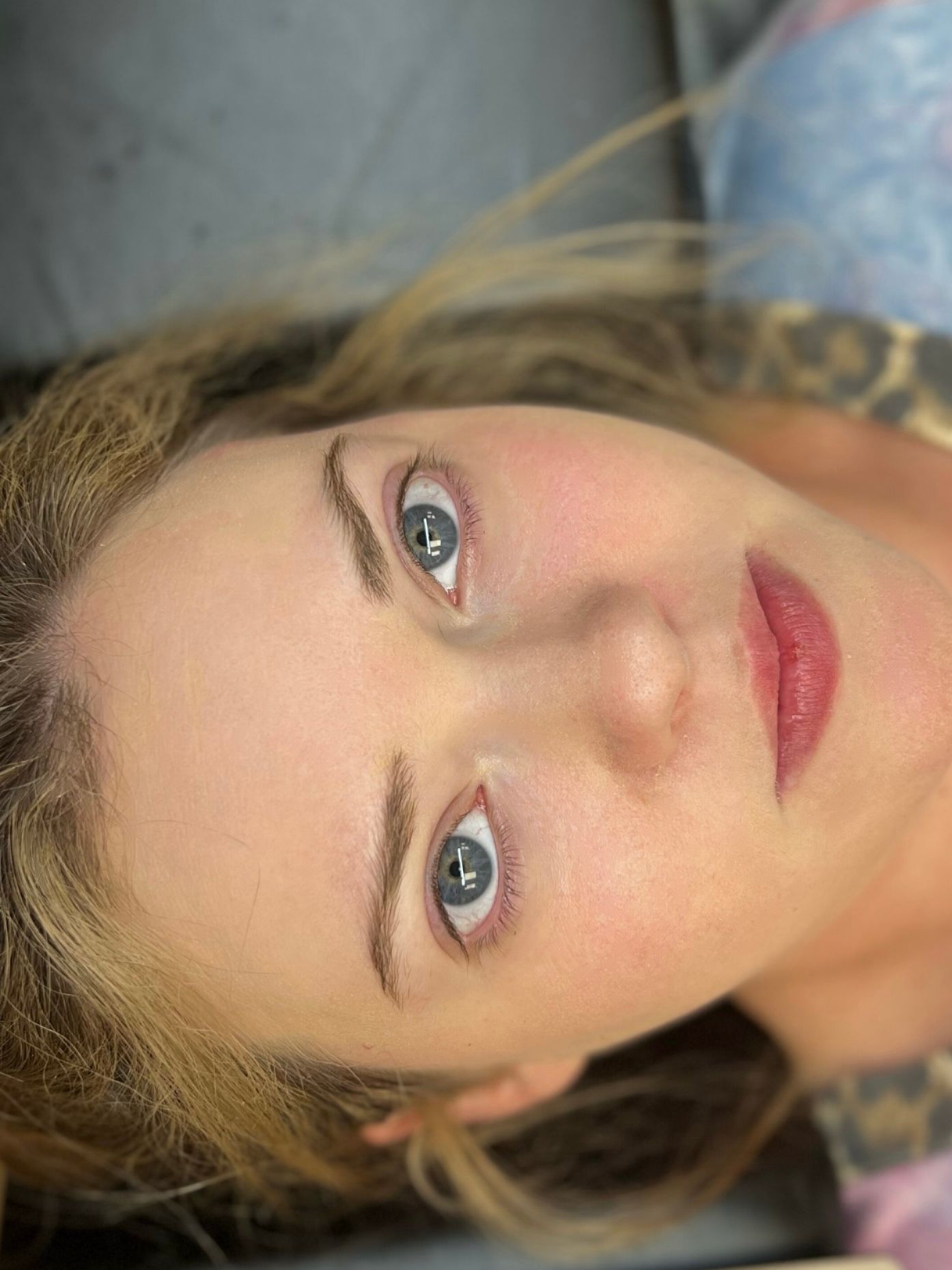 A close up of a woman 's face with blue eyes and red lips.