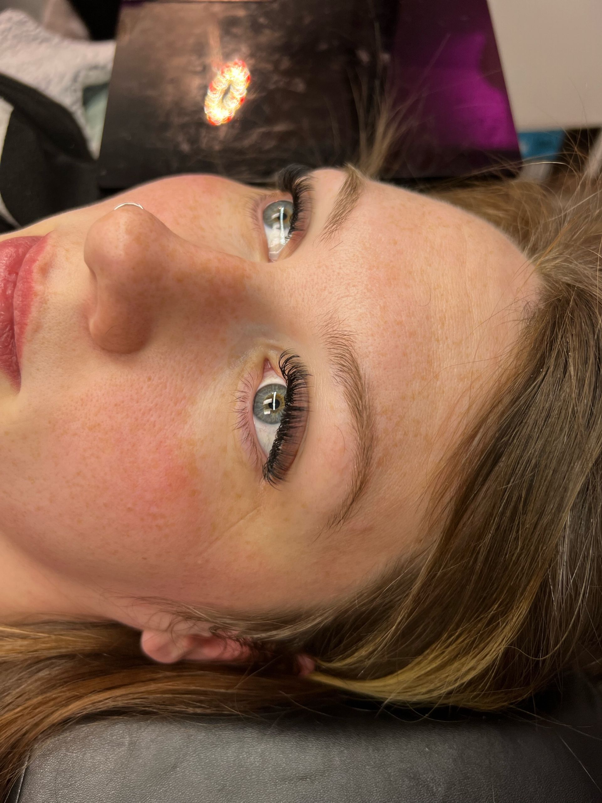 A close up of a woman 's face with a laptop in the background.