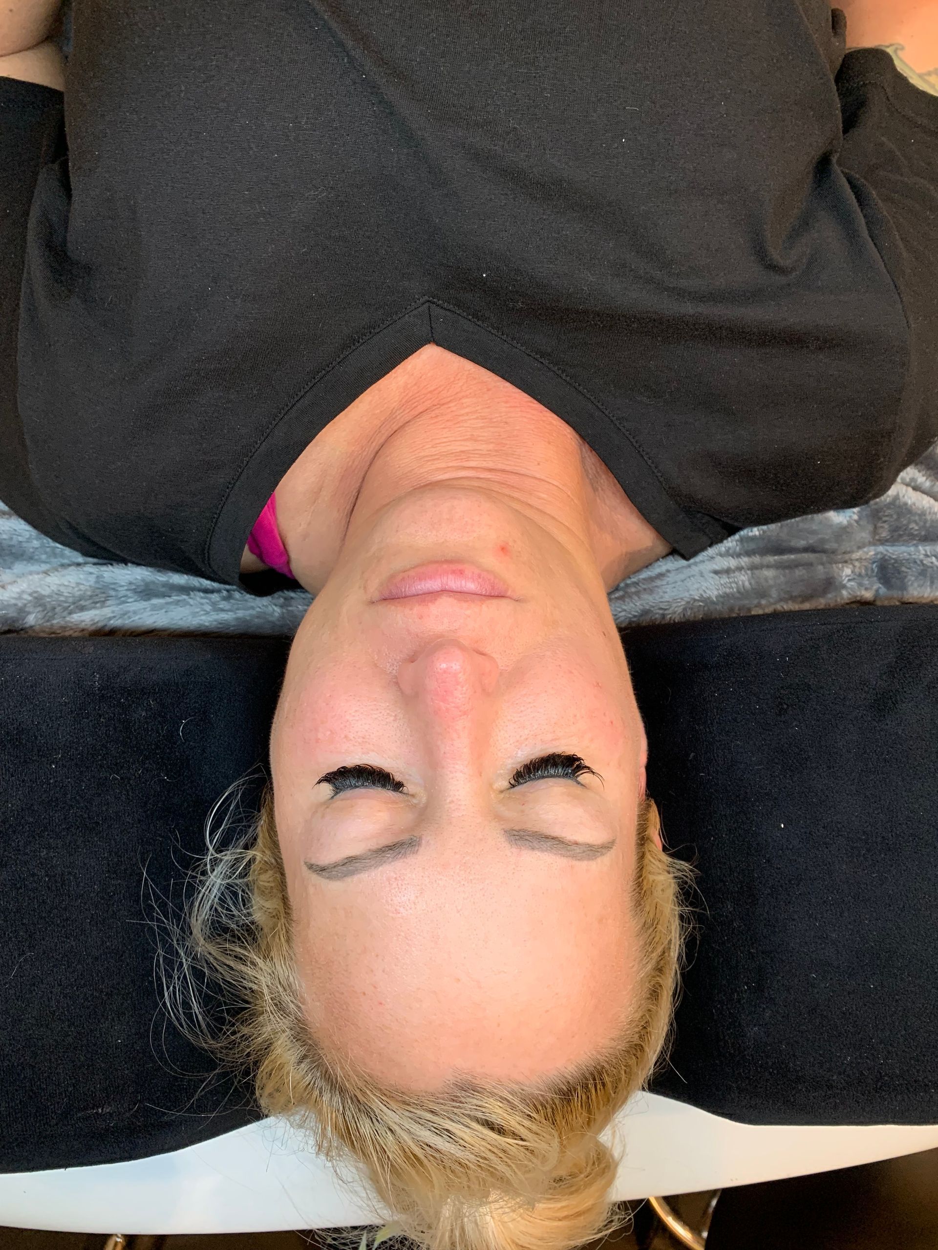 A woman is laying on her back with her eyes closed.