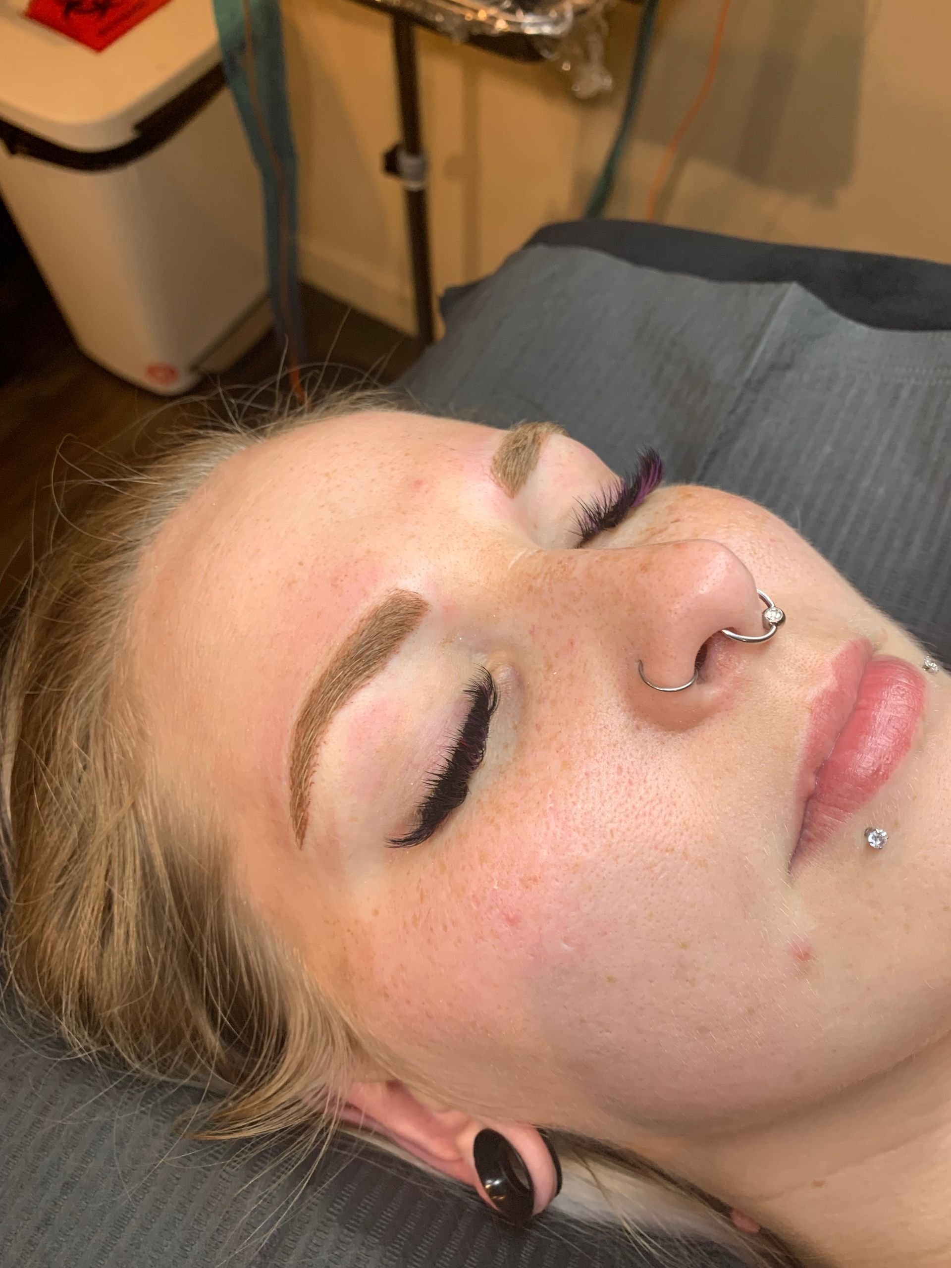 A close up of a woman 's face with her eyes closed and a nose ring.