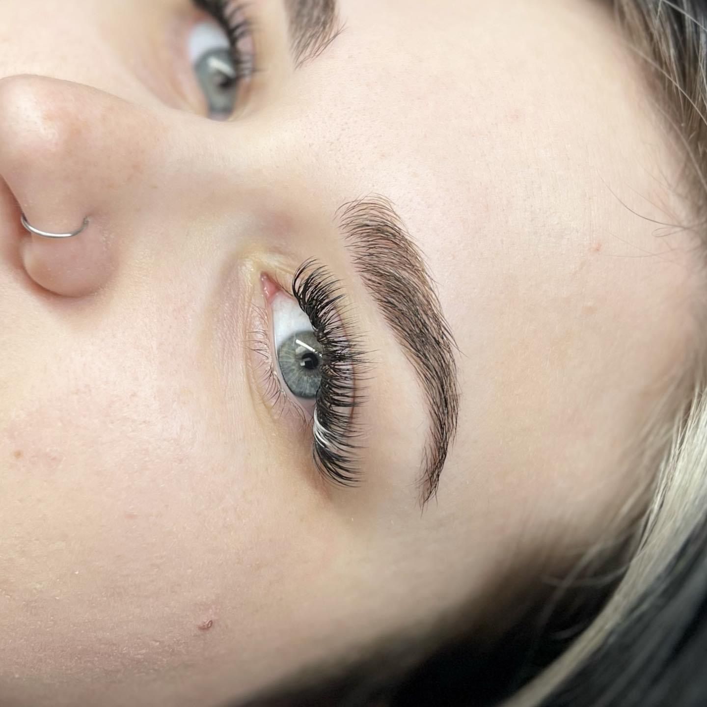 A close up of a woman 's face with long eyelashes and a nose ring.